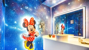 A bathroom with a starry wall mural, a Mickey Mouse figure, and a large mirror. - The Mickey and Minnie studio w/ pool & parking (Kissimmee)