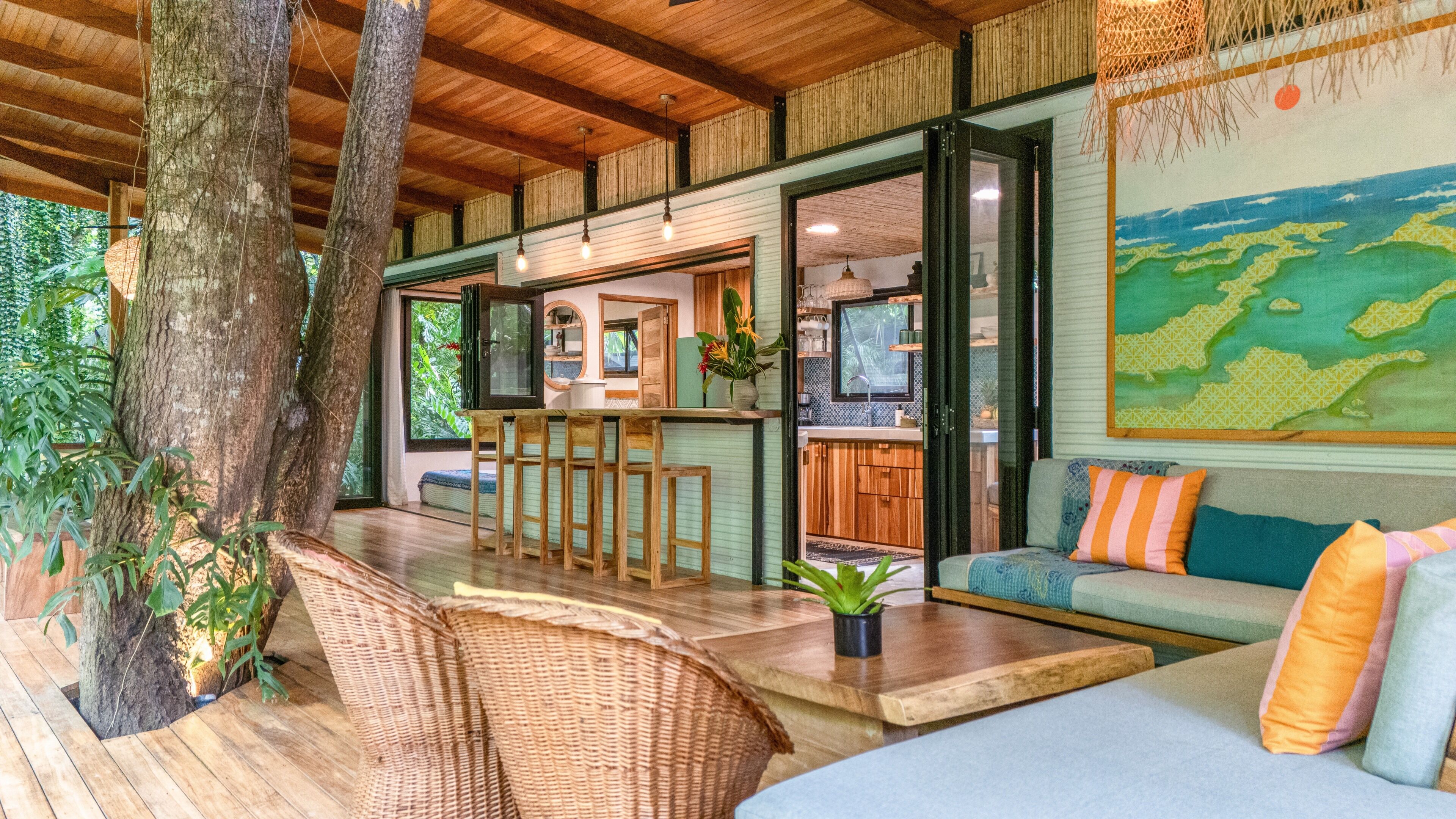 A spacious room with a wooden ceiling, a dining area, a kitchen, and a large window.