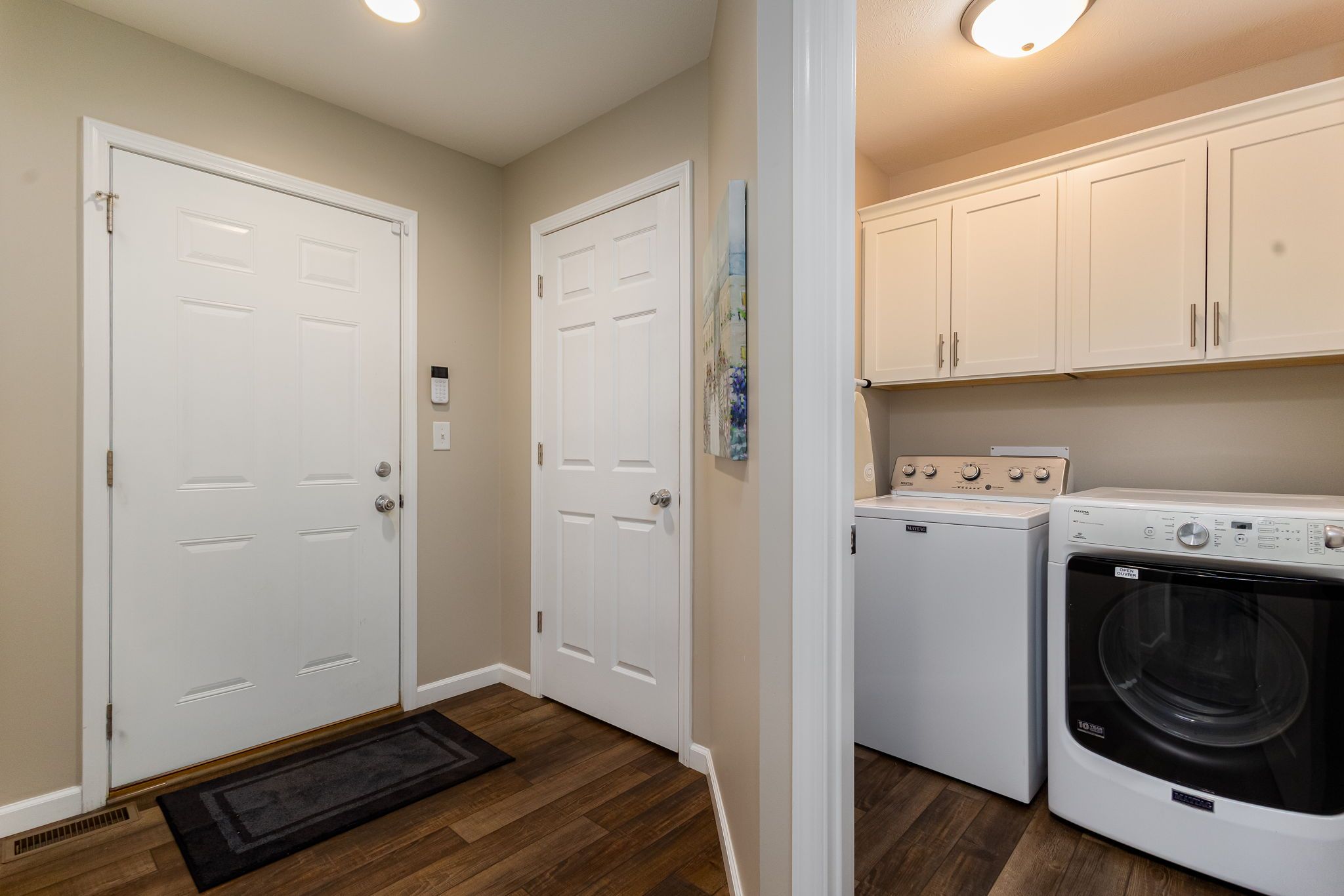 A laundry room with two white doors, a washing machine, and a dryer.