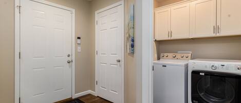 A laundry room with two white doors, a washing machine, and a dryer.