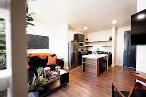 A modern kitchen with a refrigerator, microwave, and wooden cabinets.