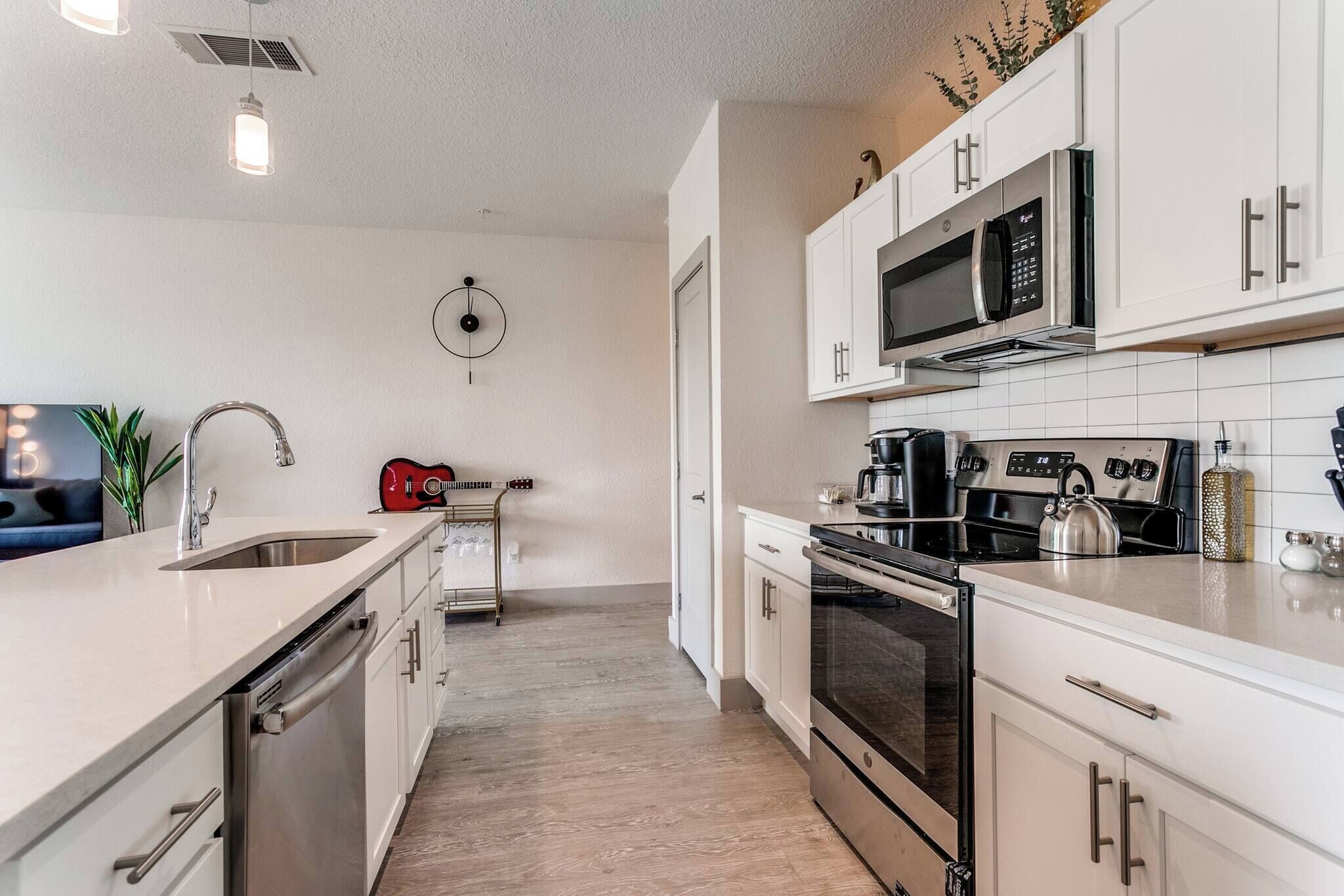 A modern kitchen with white cabinets, stainless steel appliances, and a central island with a sink.