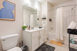 A modern bathroom with a toilet, sink, mirror, shower, and a towel rack. - Riverwalk Balcony Views Walk to Pearl Pool Parking Option 2 Free Parking (San Antonio)