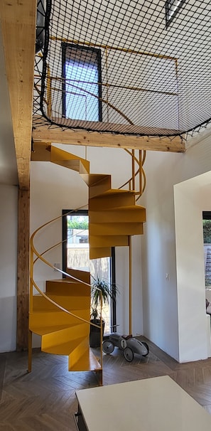 A modern interior with a spiral staircase, wooden beams, and a view through a window. - Family home (Le Teich)