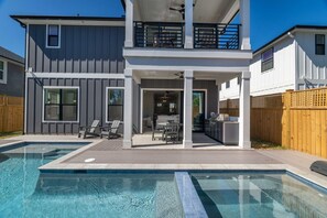 Ein modernes, zweistöckiges Haus mit Swimmingpool, Außenbereich zum Sitzen und Grillplatz.