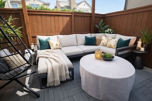 Eine Holzterrasse mit einer Eckcouch, einem runden Couchtisch und einem Hängesessel.
