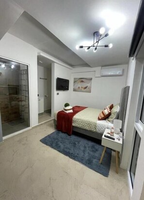 Une chambre à coucher avec un lit, une table de chevet et un téléviseur fixé au mur.