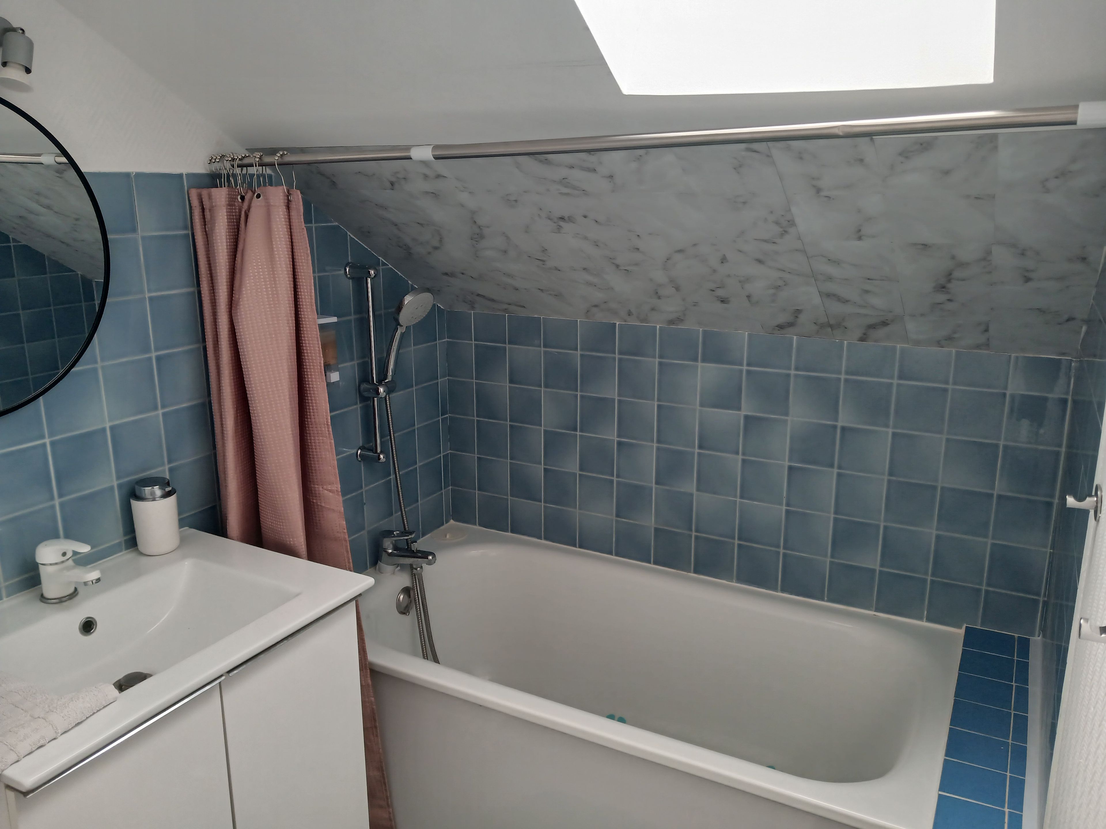 Een badkamer met een bad, een douche, een wastafel en een spiegel.