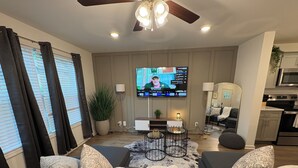 Un salon équipé d’un téléviseur, d’un canapé, d’une table basse et d’un ventilateur de plafond.