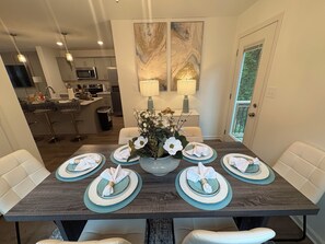 A dining table set with plates, napkins, and a vase of flowers. - Travel Nurse Friendly Dedicated Workspace+Fast Wifi Near Fortcampbell+Hospitals (Clarksville)