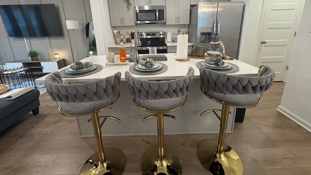 Une cuisine moderne dotée d’un îlot central, de tabourets de bar et d’un coin repas.