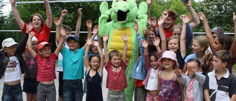Un grupo de niños y un adulto con un disfraz de mascota en un parque.