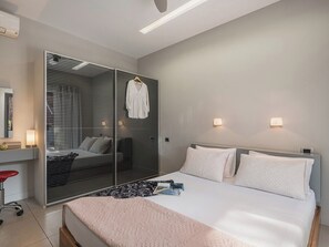A modern bedroom with a bed, bedside lamps, a wardrobe, and a desk with a chair. - Kalathas Waterfront Villa (H32M+VR9 Kalathas, Greece)