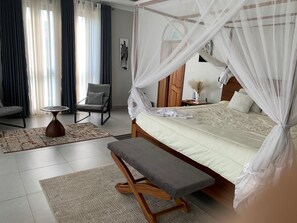 Une chambre à coucher avec un lit à baldaquin, un banc, une chaise, une petite table et un tapis.