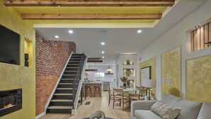 A modern interior with a staircase, a fireplace, a dining area, and a living room. - The Newbold Retreat | Roof Deck + Skyline View (Philadelphia)