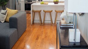 Una cocina moderna con una isla central, taburetes de bar, un refrigerador y una zona de comedor con un sofá.