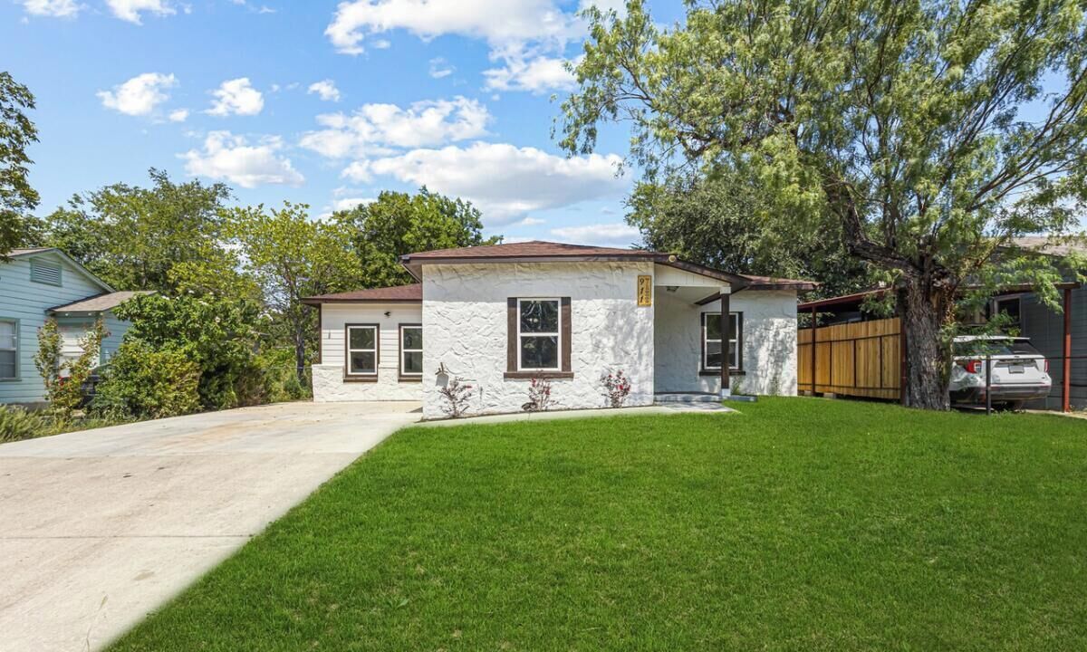 A single-story house with a front yard, a driveway, and a wooden fence.