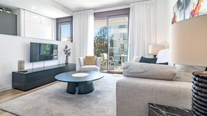 Un salon moderne doté d’un téléviseur à écran plat, d’une table basse ronde, d’un canapé et d’un coin repas avec des chaises.