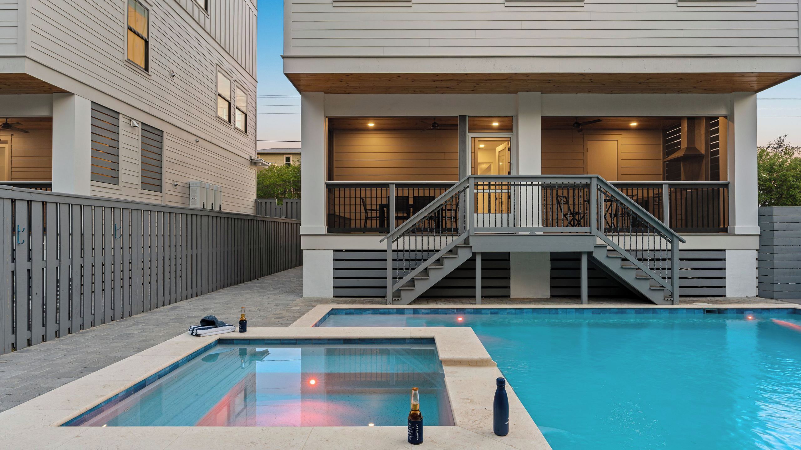 Une maison moderne dotée d’une piscine, d’une terrasse couverte et d’un escalier menant à un étage supérieur.