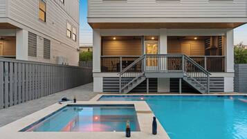 Une maison moderne dotée d’une piscine, d’une terrasse couverte et d’un escalier menant à un étage supérieur.
