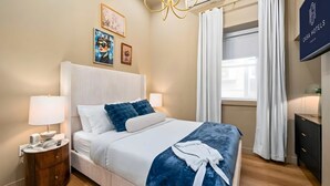 A hotel room with a bed, bedside table, lamp, artwork, and a sign indicating the hotel name. - The Mccaul Urban Retreat Near Kensington Market (Toronto)