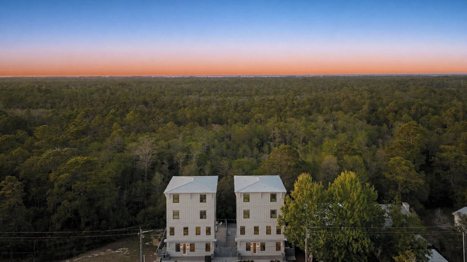 A two-story building with a symmetrical facade, surrounded by dense forest.