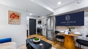 A modern hotel room with a kitchenette, a dining area, and a bed. - The Mccaul Basement Near Chinatown & AGO (Toronto)