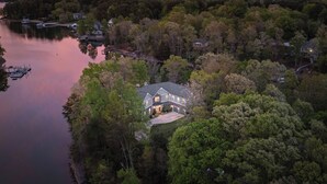 Une vue aérienne d’une grande maison entourée d’une forêt dense et bordée d’un lac.