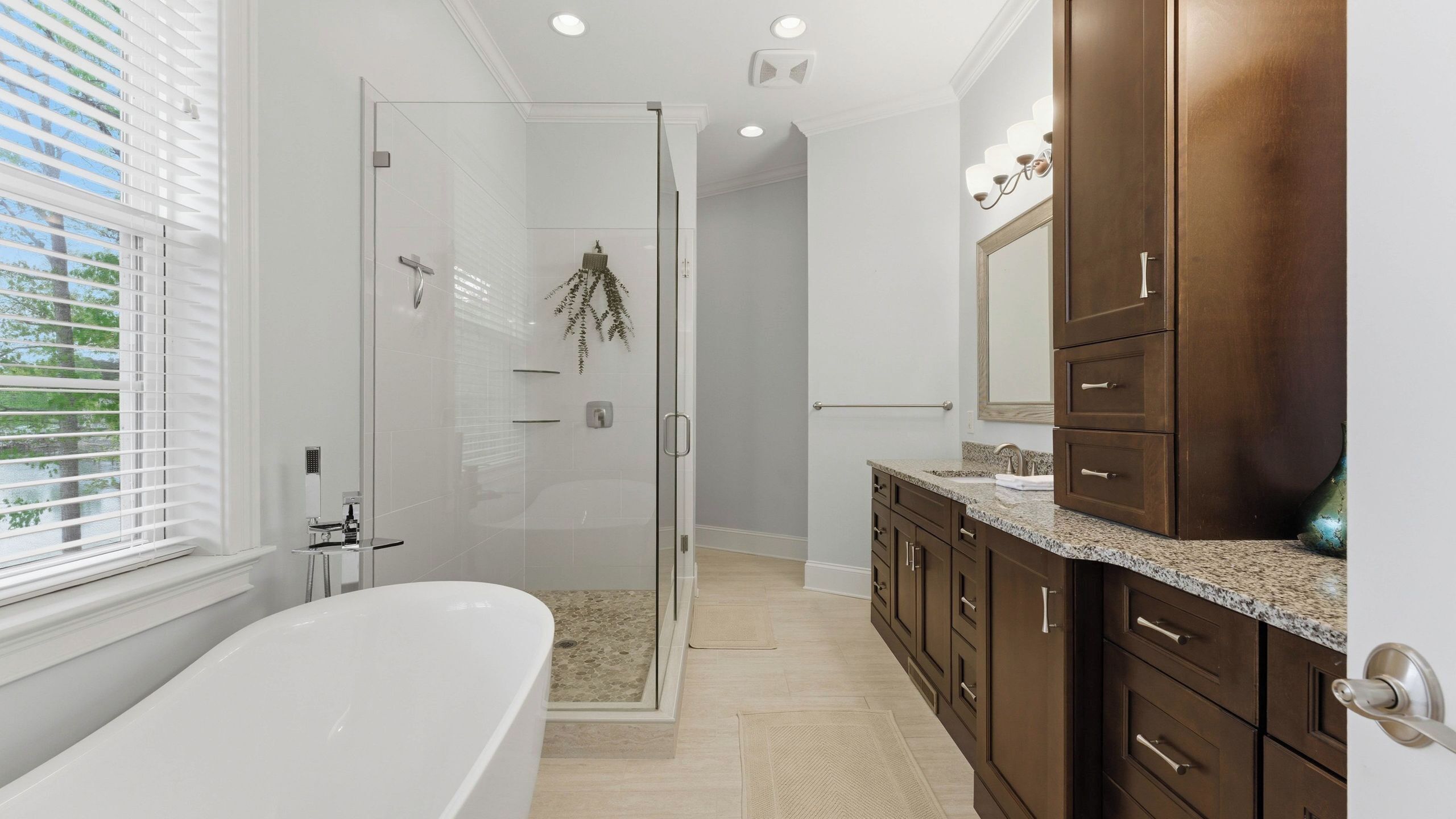 A modern bathroom with a glass shower enclosure, a freestanding bathtub, and dark wood cabinetry.