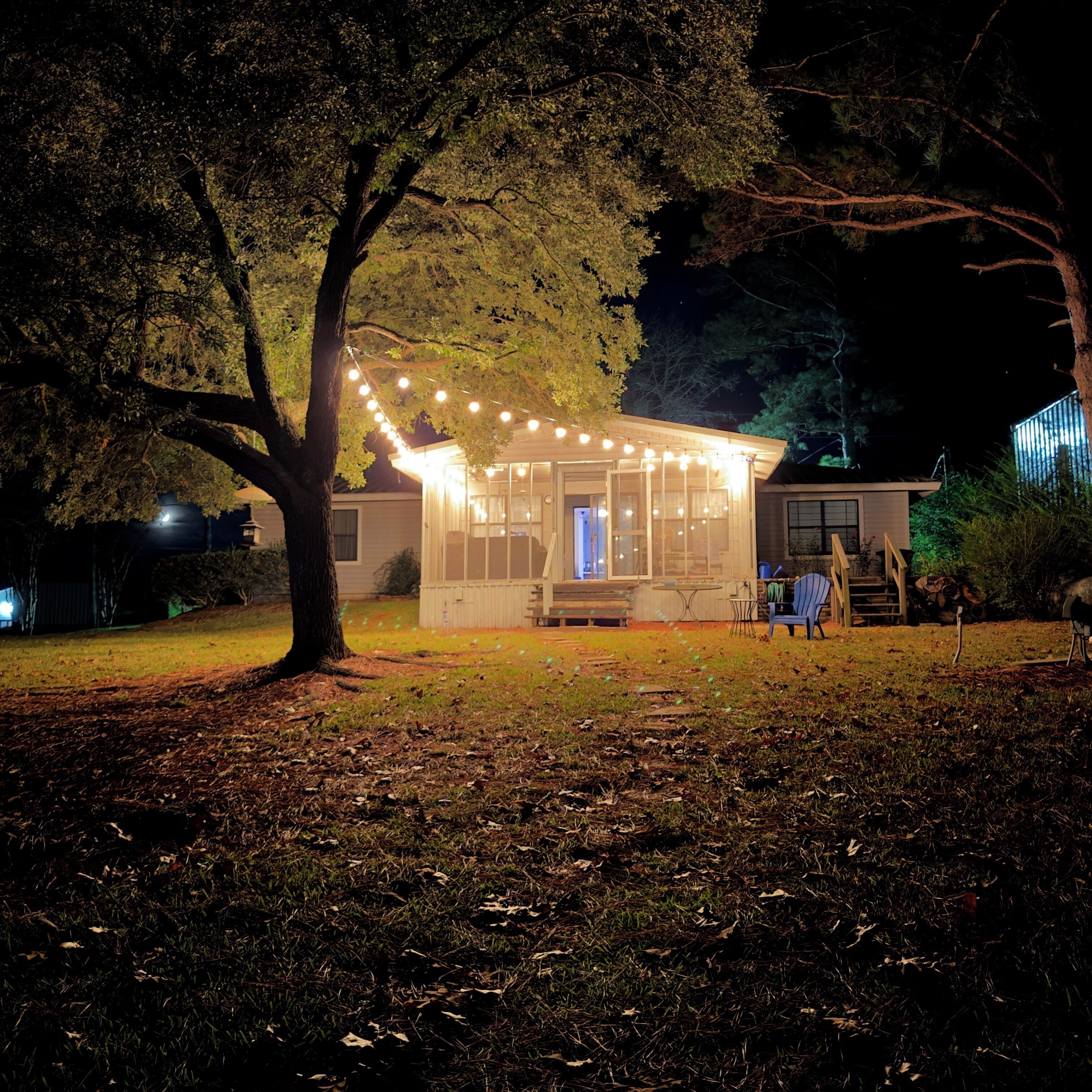 A house with a covered porch, string lights, and a tree in the foreground.