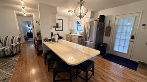 A modern kitchen with a central island, stainless steel appliances, and a dining area with a striped chair. - Waterfront 3-bedroom house, sleeps 7, pet friendly, boat dock. South Toledo Bend (Burkeville)