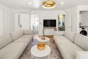 A modern living room with two sofas, a TV, and a dining area with a table and chairs. - Penthouse at Humboldt House (Denver)