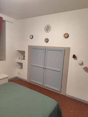 Ein Schlafzimmer mit einem Bett, einem Kleiderschrank und einem Regal mit Gegenständen.