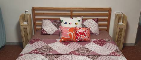 A bed with a quilt, two bedside tables, and a wall decoration.