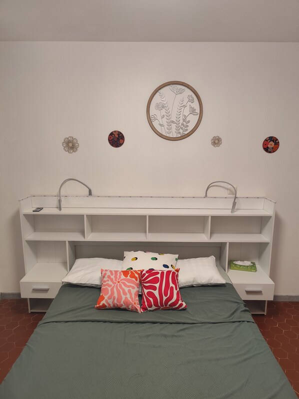 A bedroom with a bed, a white headboard, a shelf, and a wall with decorative items. - Cévennes summer pastures (Anduze)