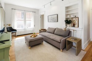 A modern living room with a sofa, ottoman, and a small side table. - Park View Apartment at Humboldt House (Denver)