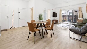 A modern living room with a dining area, a sofa, and a TV.