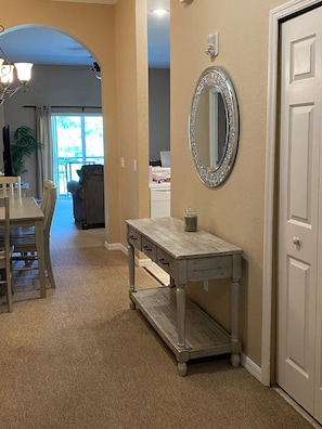 A hallway with a wooden bench, a vanity table with drawers, a mirror with a decorative frame, and a door. - Bahama Bay Resort, 3 bedroom lake/pool view with 75 inch TV. Ground floor. (Davenport)