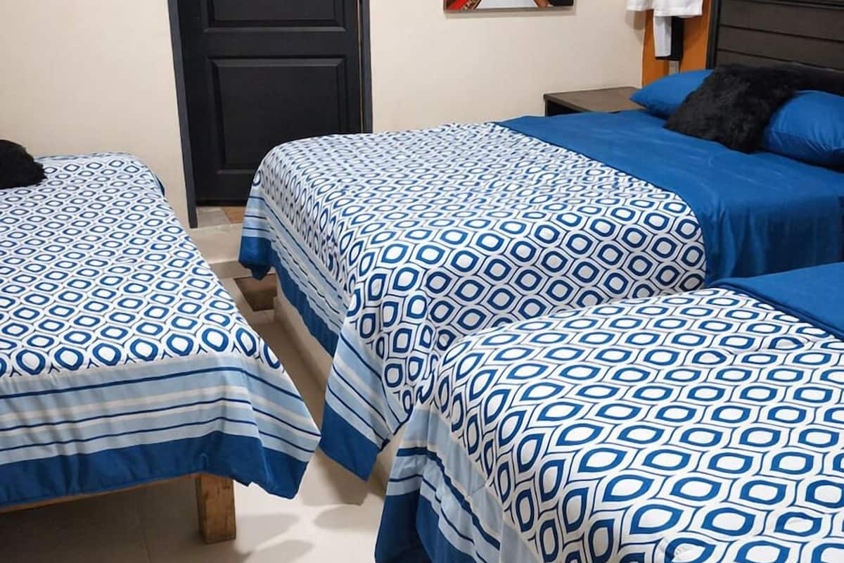 Une chambre d’hôtel avec deux lits, une porte, un appareil de climatisation, un tableau et une fenêtre avec des rideaux.