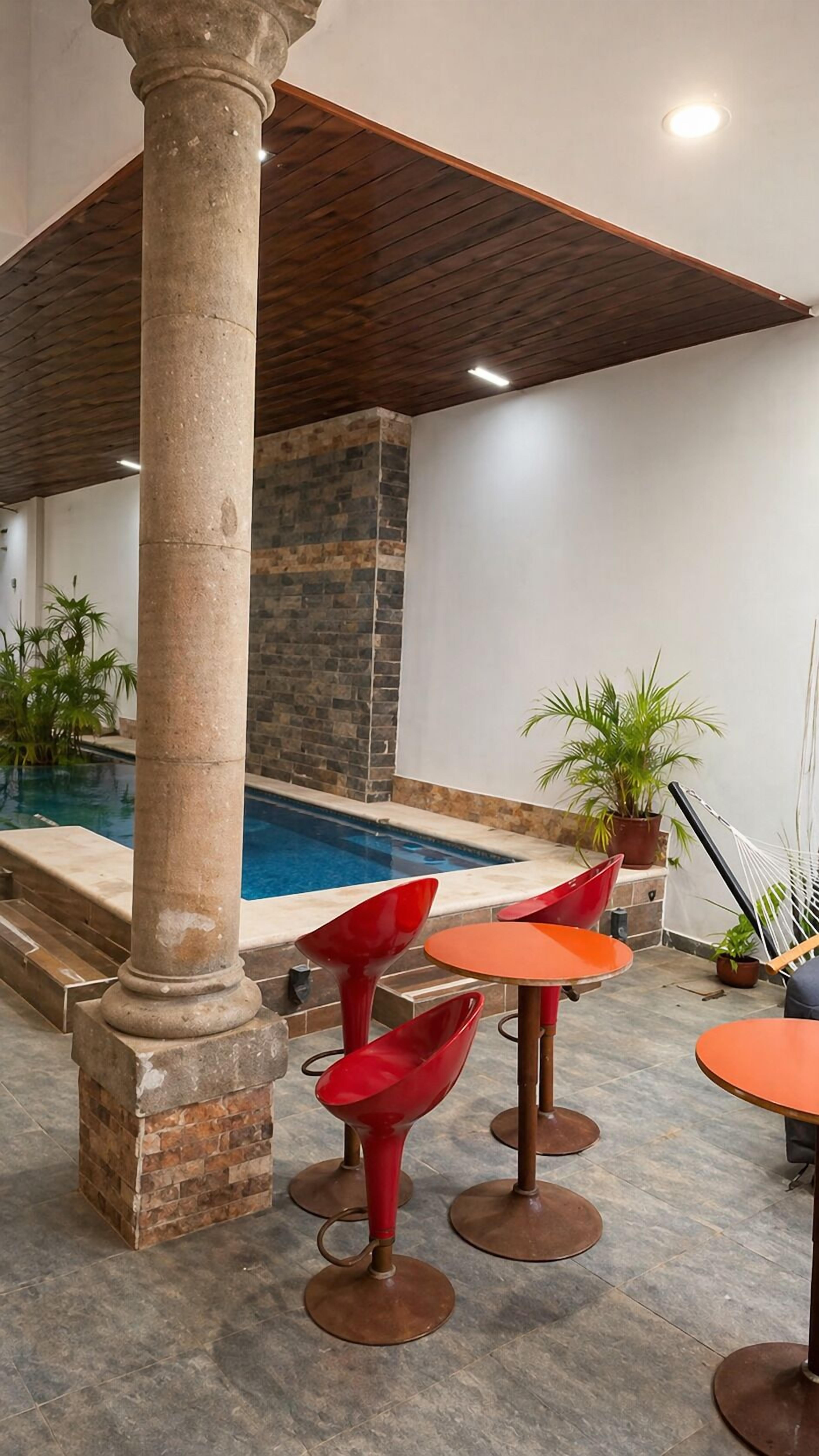 Un espace piscine intérieur agrémenté de colonnes en pierre, d’un mur en pierre et de mobilier contemporain.