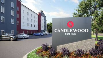 Un letrero de hotel que dice 'CANDLEWOOD SUITES' y un edificio moderno con muchas ventanas.