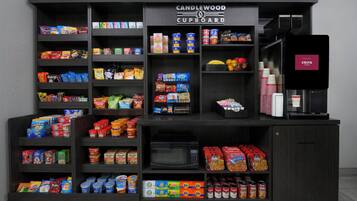 Una kitchenette con estantes llenos de bocadillos, condimentos y una máquina de café.