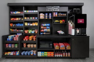 Una kitchenette con estantes llenos de bocadillos, condimentos y una máquina de café.