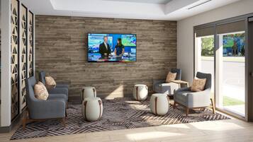Un vestíbulo moderno con una televisión grande, asientos cómodos y una pared de acento de madera.