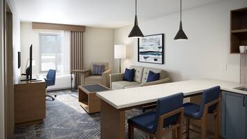 A modern hotel room with a dining area, a sofa, a desk, and a view of the outdoors.