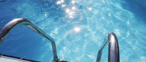 A clear pool with visible water clarity and sunlight reflections.