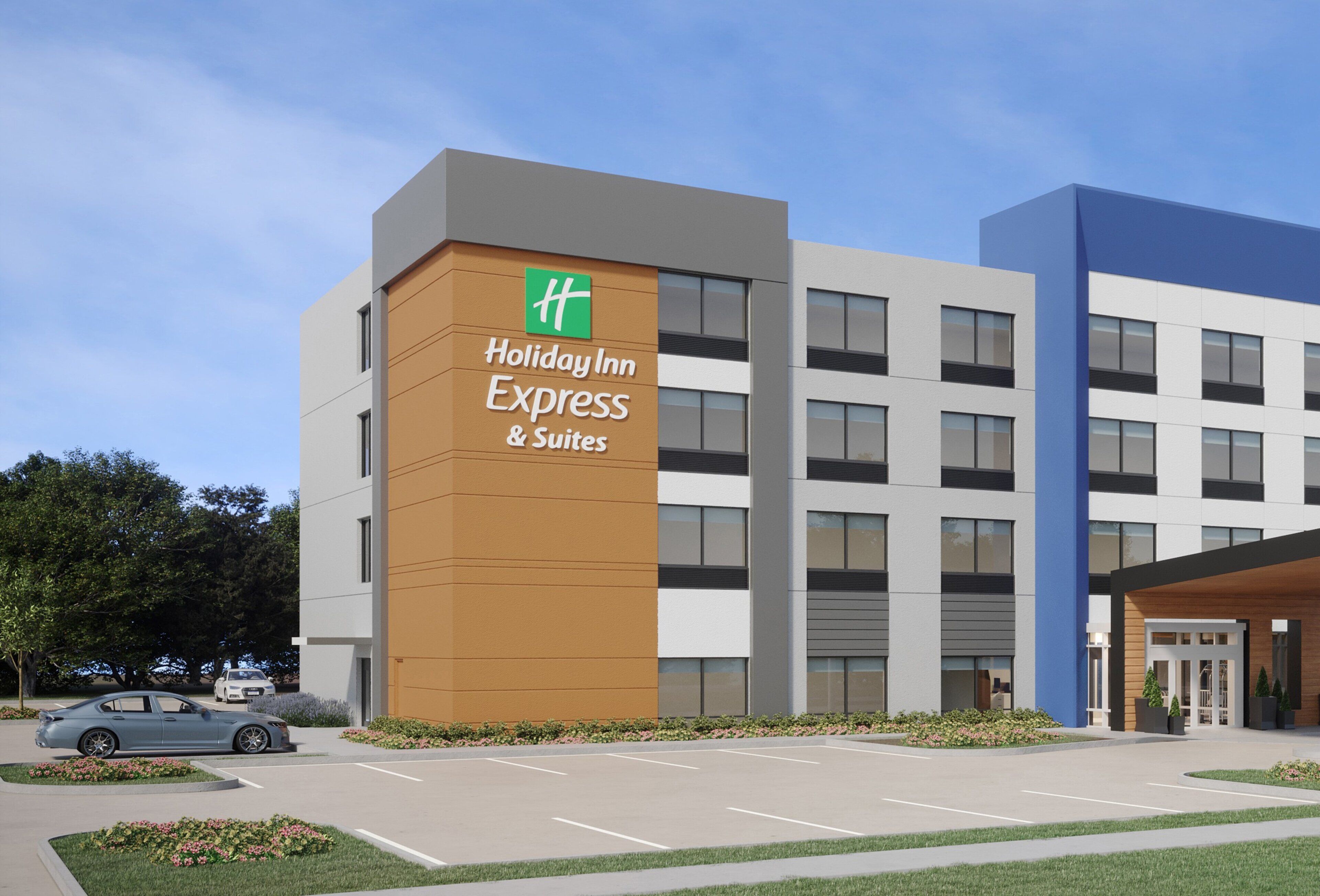 A Holiday Inn Express & Suites building with a modern design, parking lot, and a car in the foreground.