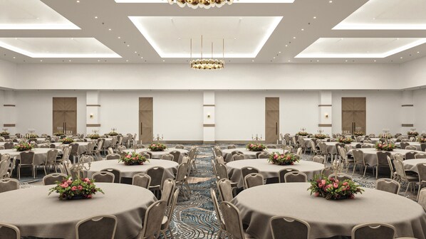 A large conference room with round tables, chairs, and a patterned carpet.