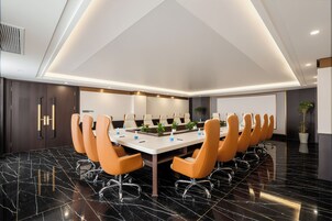 A conference room with a long table, multiple chairs, and a modern ceiling design.