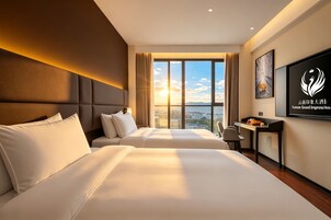 A hotel room with two beds, a desk, and a large window with a city view.